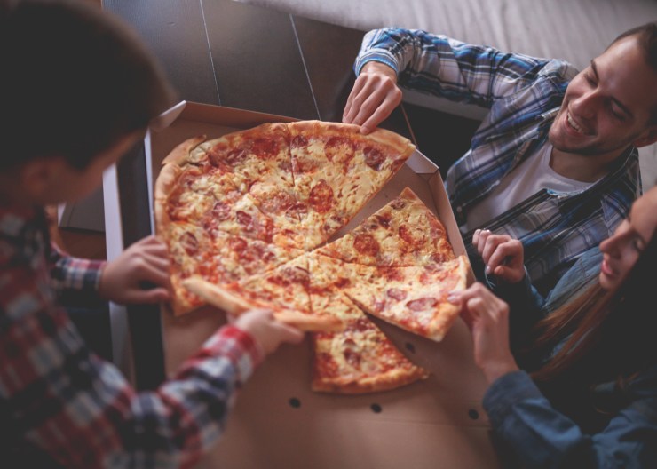 Young family with son eating pizza at home